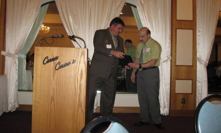 Two men standing at a wooden podium during a banquet presentation