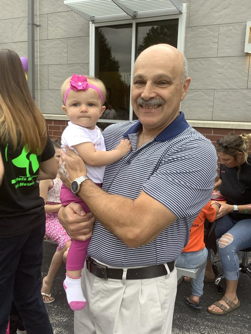 Dr. Ronald J. Busack holding a child at a community event outside the hospital