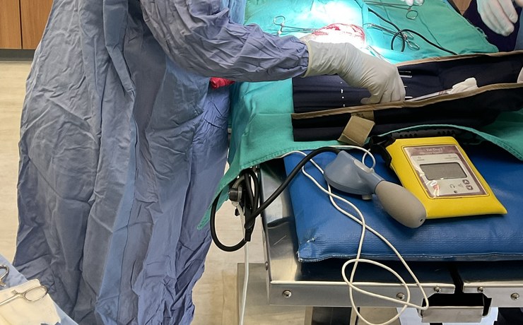 Staff in surgical gowns monitor a patient at an anesthesia table